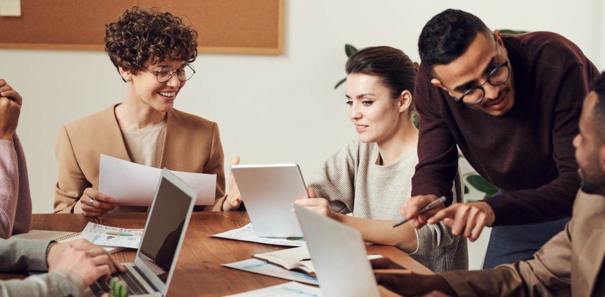 group of workers sat around meeting table with computers