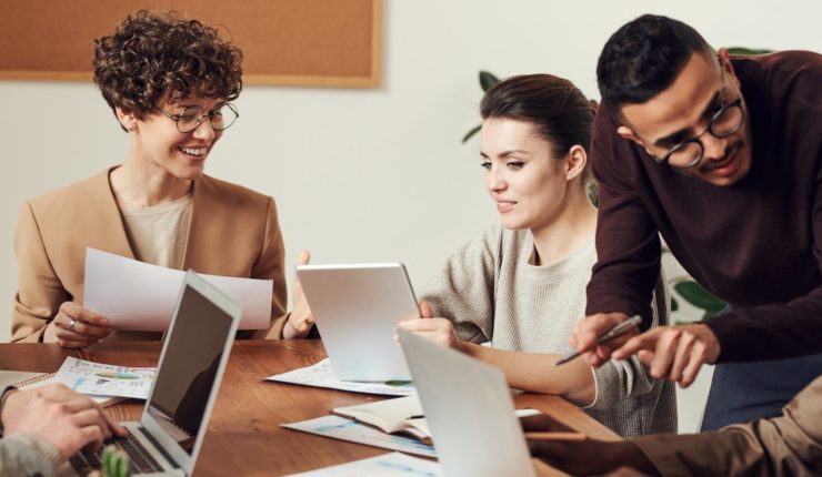 group of workers sat around meeting table with computers