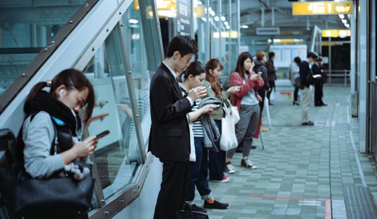 people on train platform on phones