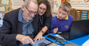 Woman and young boy helping elderly man with an ipad