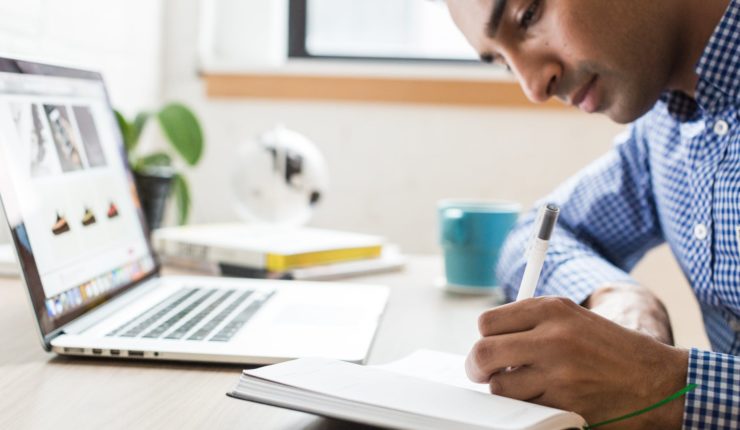 man writing in notebook