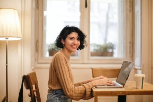 Woman in baige top working on laptop