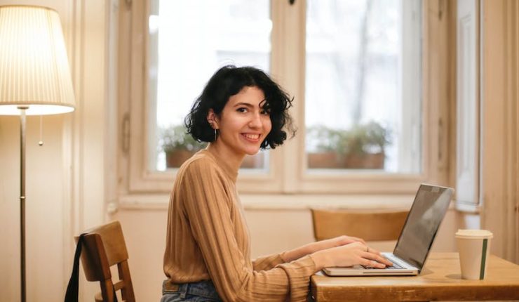 Woman in baige top working on laptop