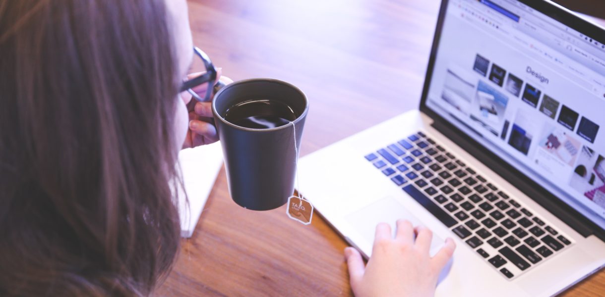 woman working on a laptop drinking tea