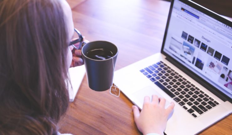 woman working on a laptop drinking tea