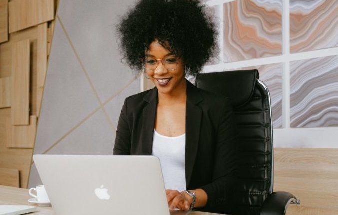 Woman in black blazer working on laptop