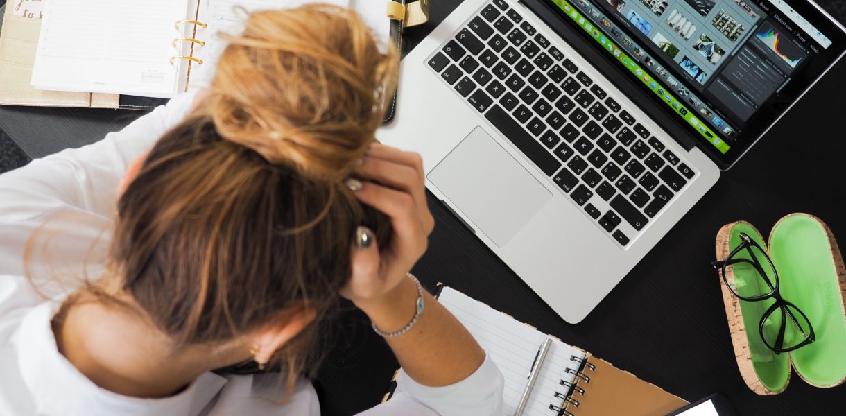 girl head in hands over her laptop