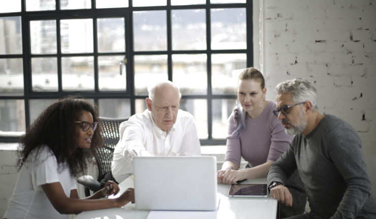 group m/f having a meeting pointing at a laptop