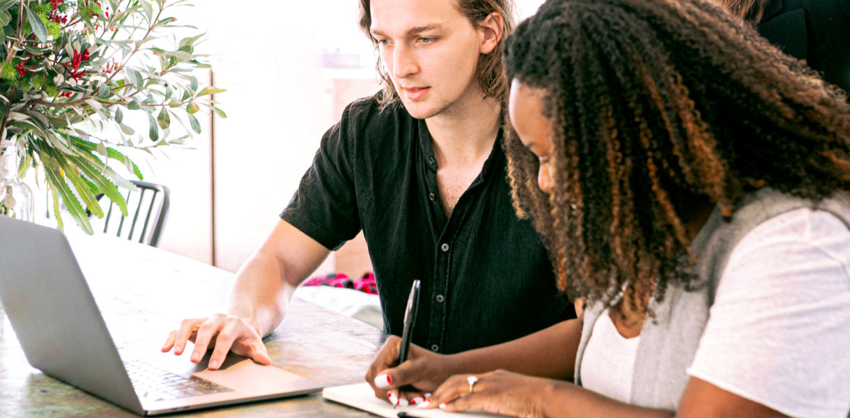 man working on laptop while lady takes notes