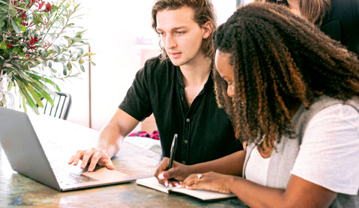 man working on laptop while lady takes notes