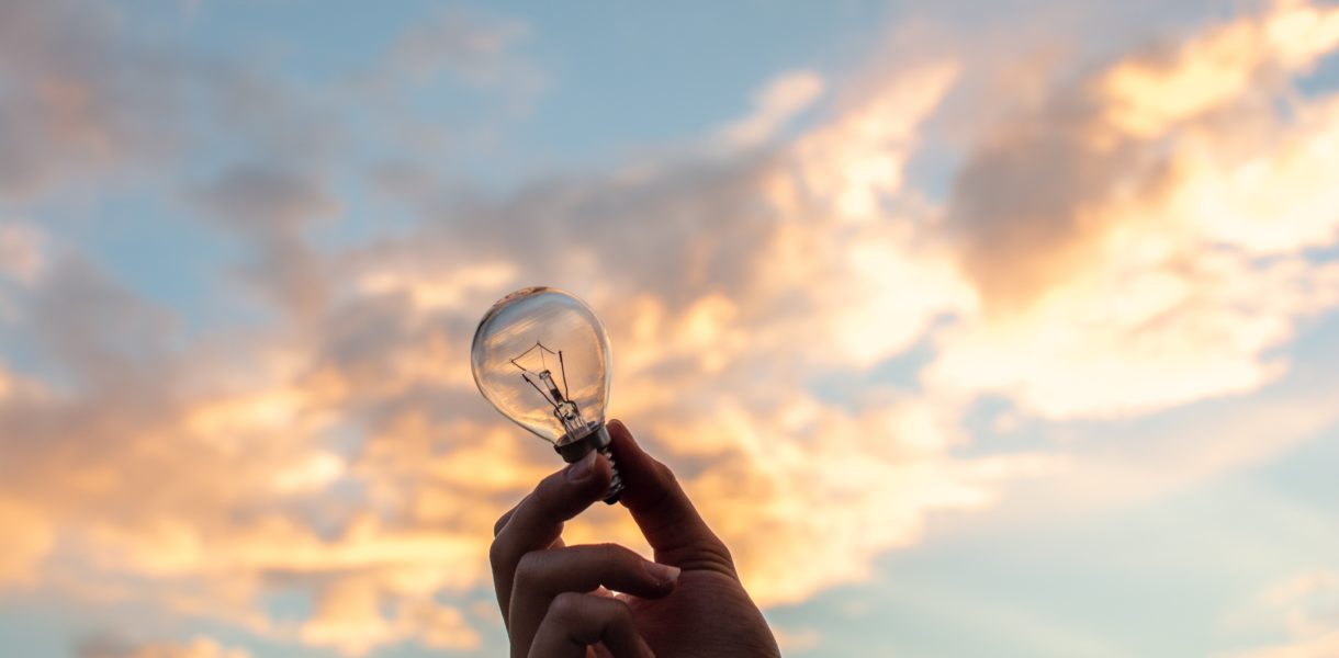 A hand holding a lightbulb to the sky