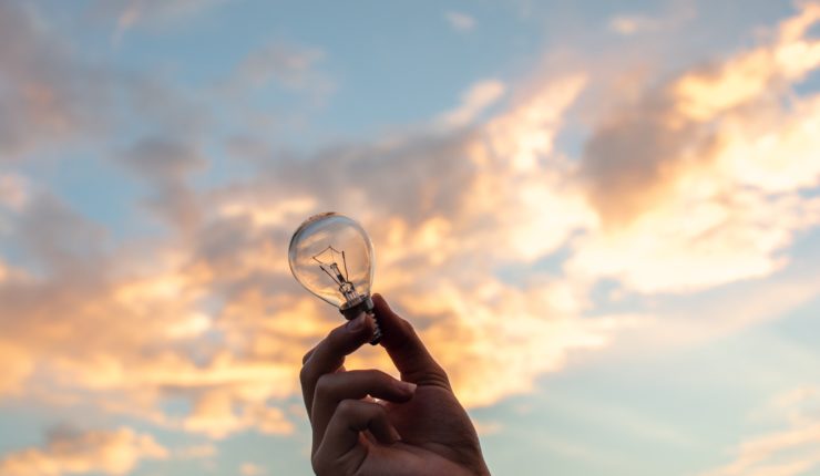 A hand holding a lightbulb to the sky