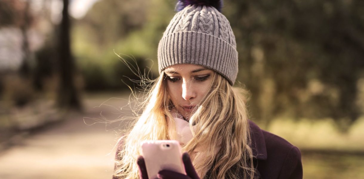 woman-in-violet-coat-holding-white-smartphone-