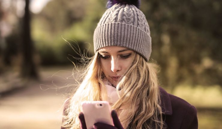 woman-in-violet-coat-holding-white-smartphone-