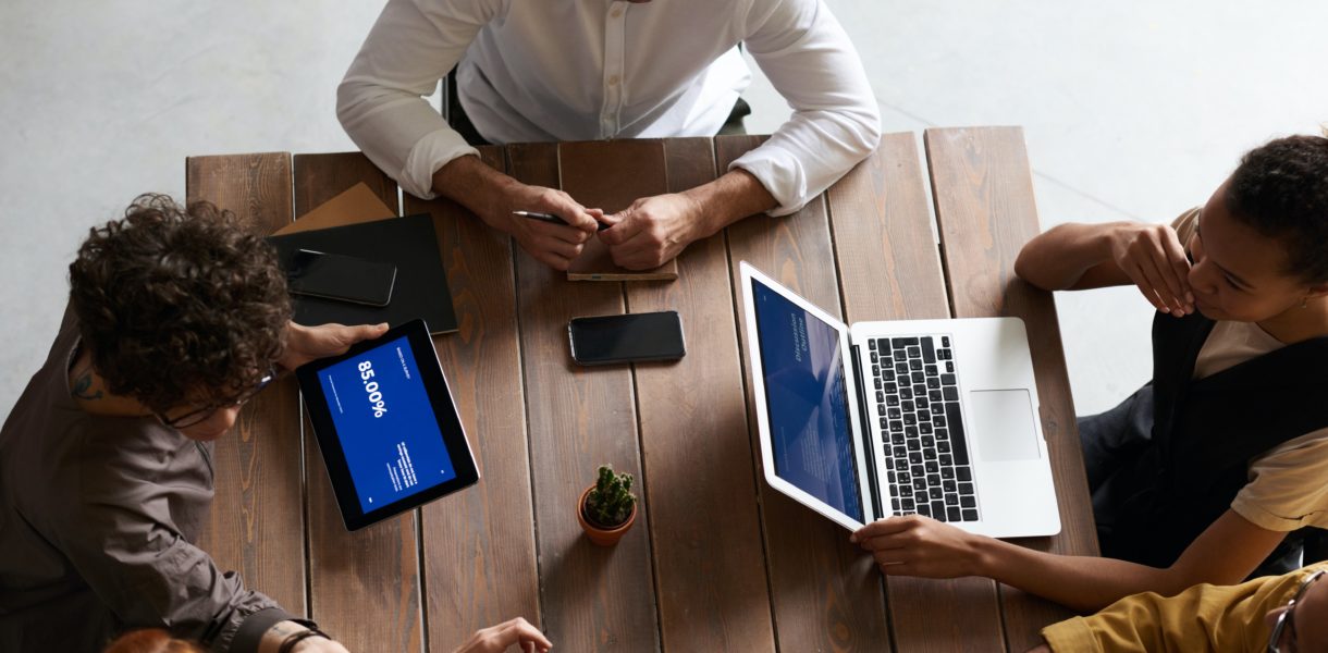 group of people at a table working on laptops