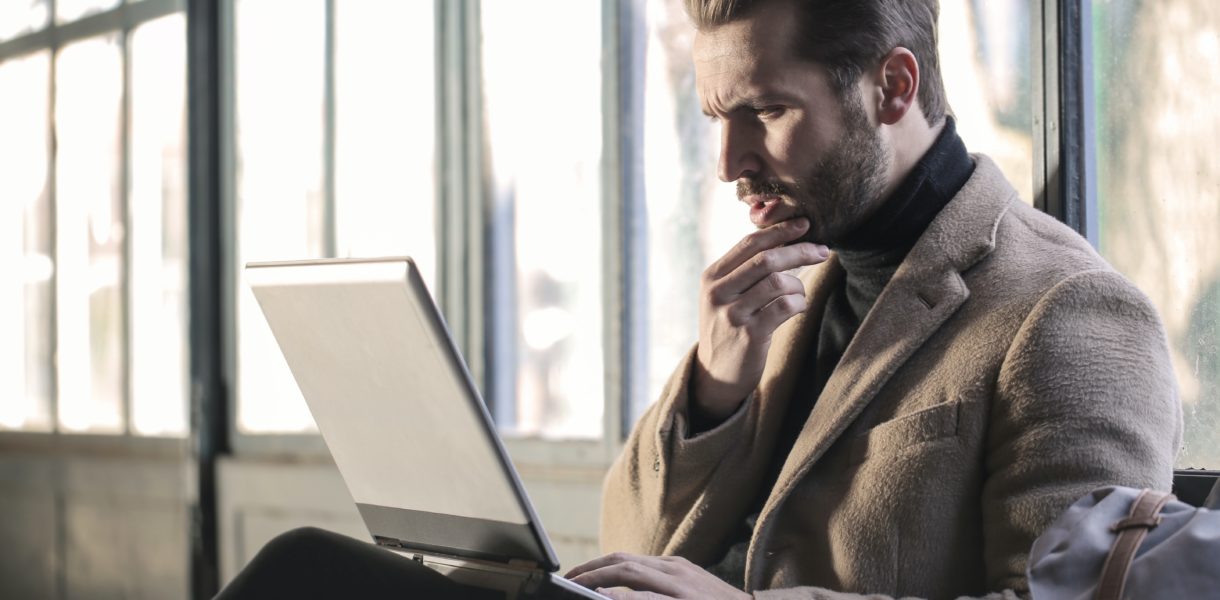 Man confused sat using a laptop