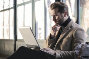 Man confused sat using a laptop