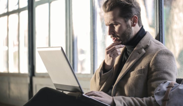Man confused sat using a laptop
