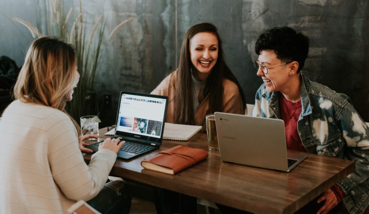 3people sat round a table with laptops