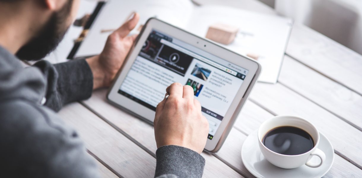 Male using an Ipad with a coffee on the table