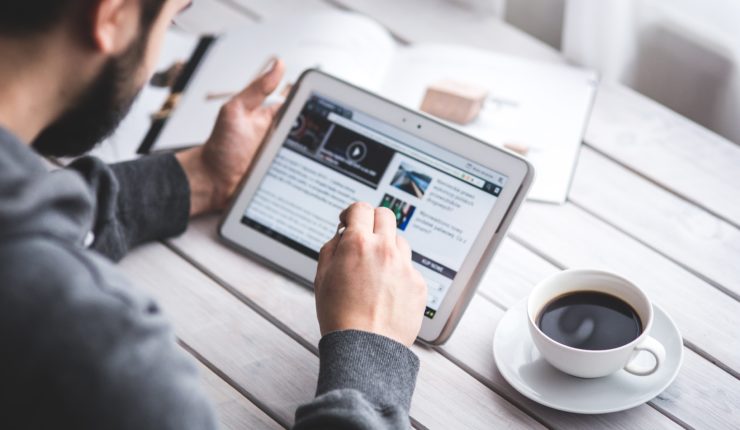 Male using an Ipad with a coffee on the table