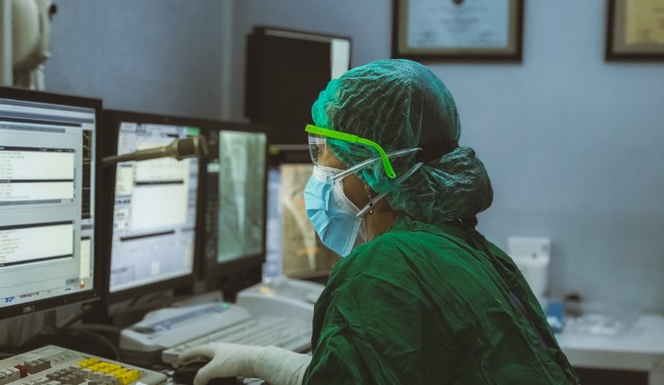 Doctor using computer wearing face covering
