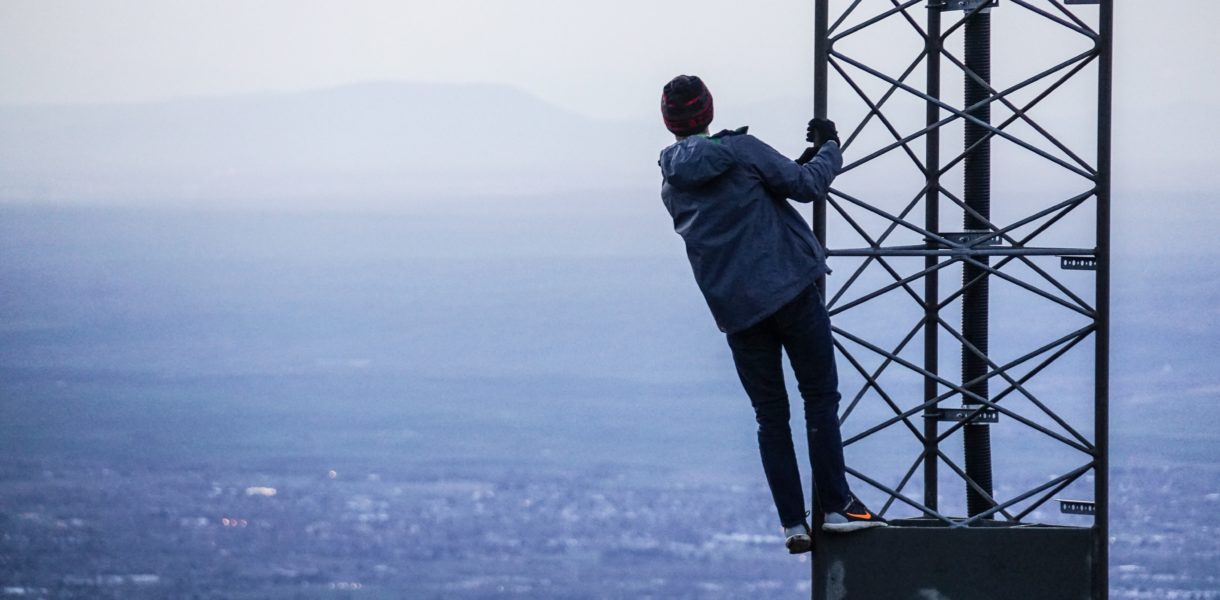 a man climbing a phone mast