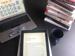 Pile of books on desk ipad and laptop