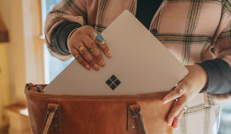 a woman putting microsoft laptop in a bag