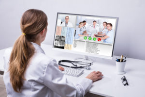 Rear,View,Of,A,Female,Doctor,Video,Conferencing,With,Colleagues