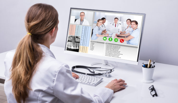 Rear,View,Of,A,Female,Doctor,Video,Conferencing,With,Colleagues