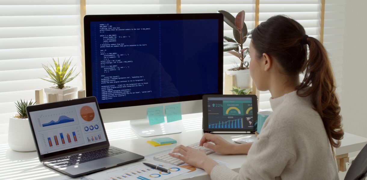 Woman using the computer and 2 other devices sat at a desk