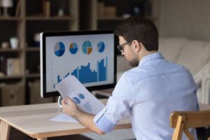 Focused,Millennial,Business,Man,Analyzing,Marketing,Reports,On,Desktop,Monitor,
